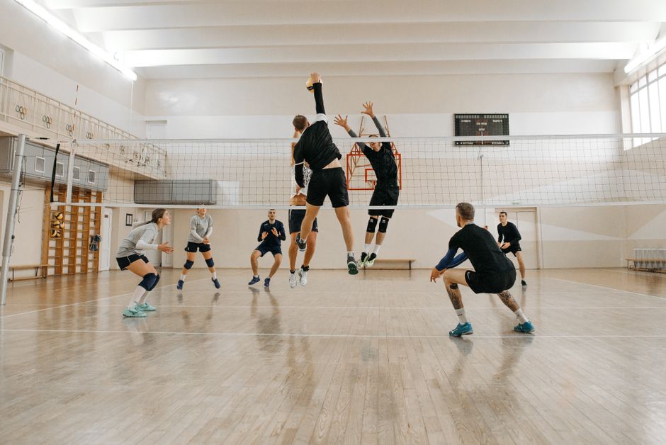Men and women engaged in a competitive indoor volleyball match, showcasing teamwork and athleticism.