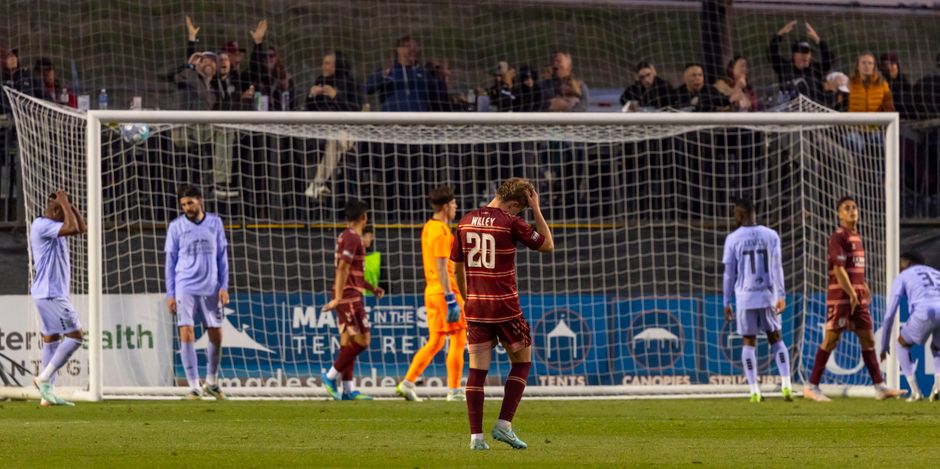 Soccer players express disappointment after missing a goal during a night match.