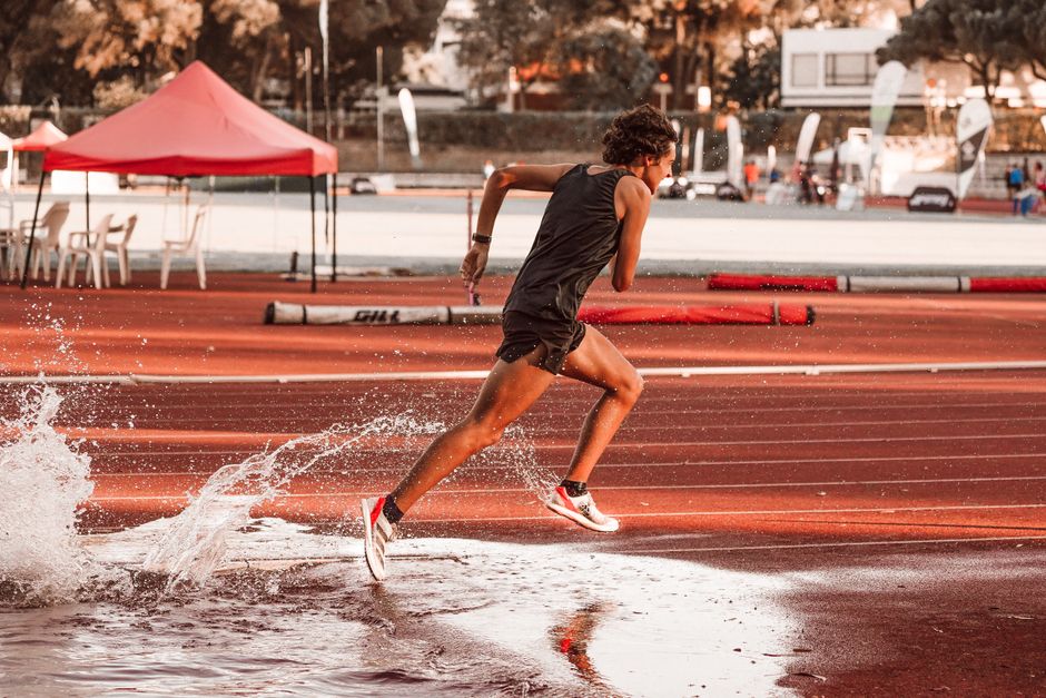 Dynamic shot of an athlete sprinting on a wet track, capturing motion and energy.