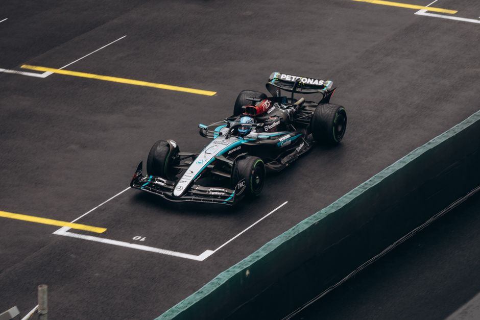 Dynamic shot of a Formula One car racing on wet asphalt, showcasing speed and precision.