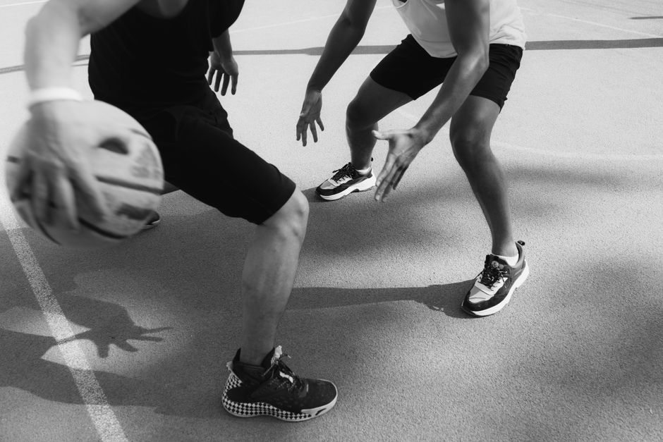 Monochrome image capturing intense basketball action and dribbling on the court.